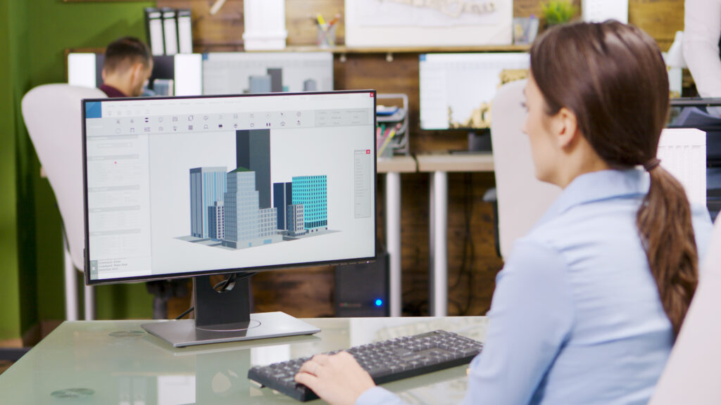 A imagem mostra uma mulher operando seu computador e utilizando a metodologia BIM em um escritório de projetos.